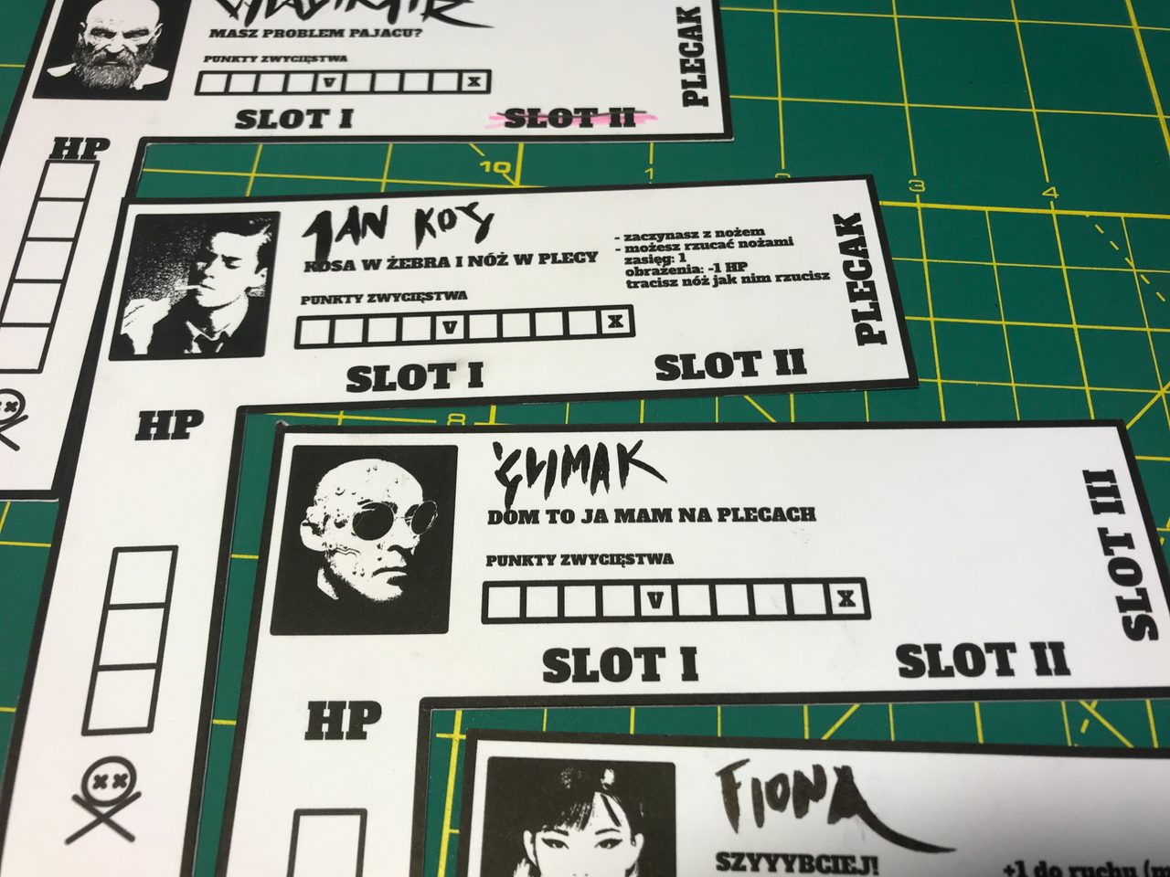 Black-and-white prototype character sheets showing portraits, health, equipment slots, and victory point tracks.