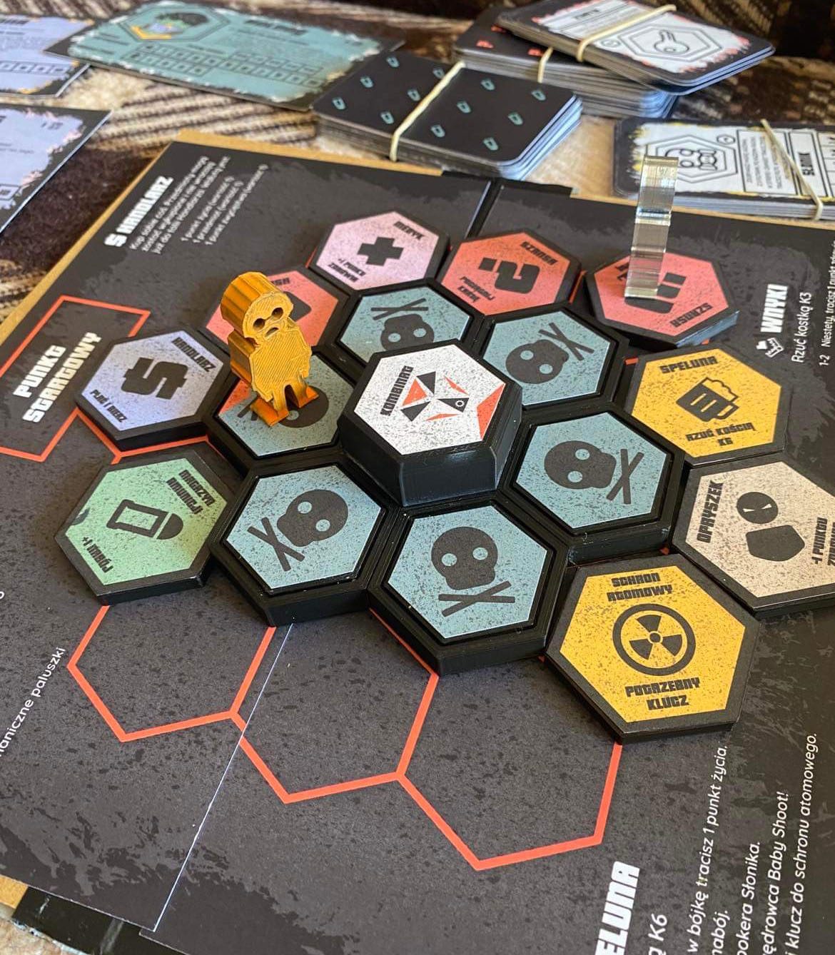Finished Kombinat board with 3D-printed hexagonal tiles, an orange pawn, character boards, and card decks.
