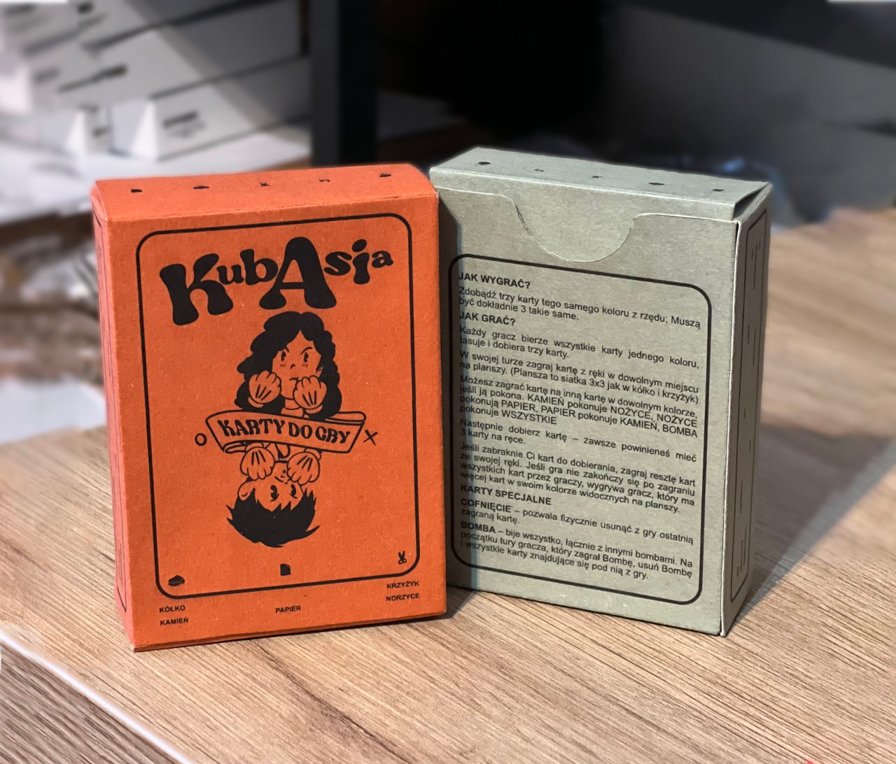 Two handmade ToeShamBo boxes showing the illustrated orange front and Polish rules on the green back.